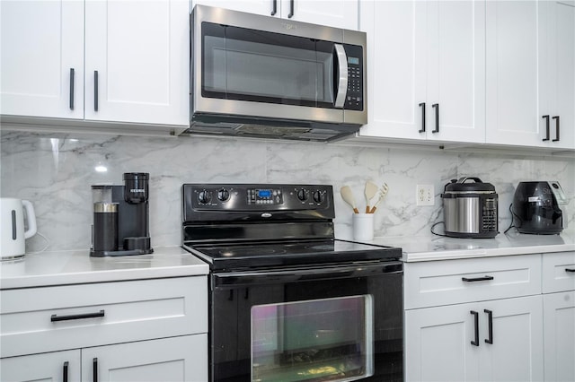 17614 Woodcrest Way, Clermont, FL 34714 - kitchen featuring stainless steel microwave, electric range, backsplash, white cabinets, and light countertops