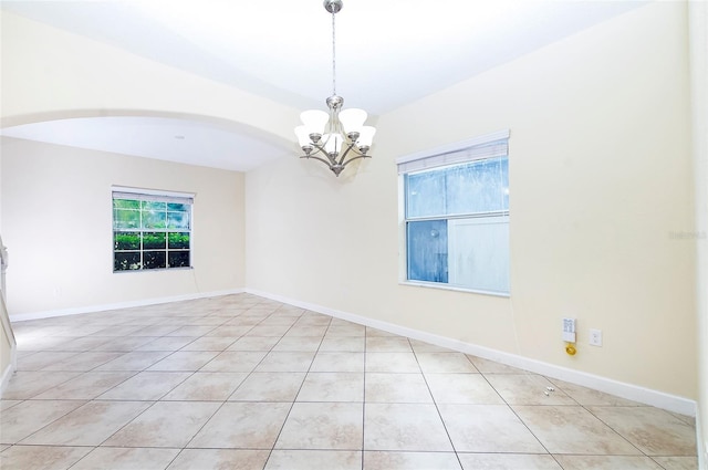 1748 Thetford Cir, Orlando, FL 32824 - empty room featuring light tile patterned floors, a chandelier, arched walkways, and baseboards