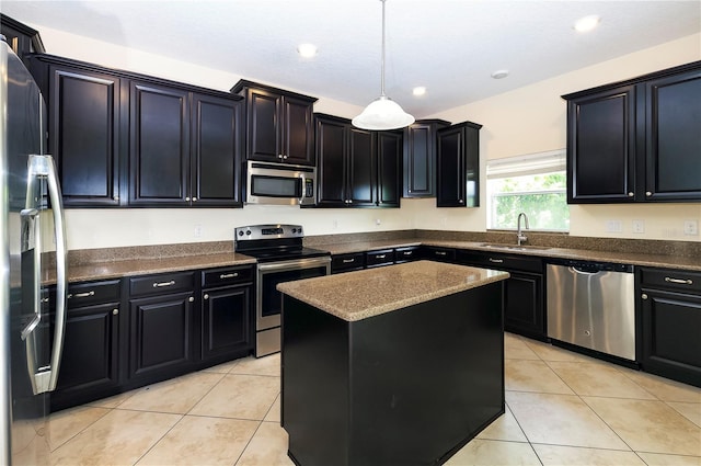 1748 Thetford Cir, Orlando, FL 32824 - kitchen featuring stainless steel appliances, dark cabinetry, a sink, light tile patterned floors, and hanging light fixtures