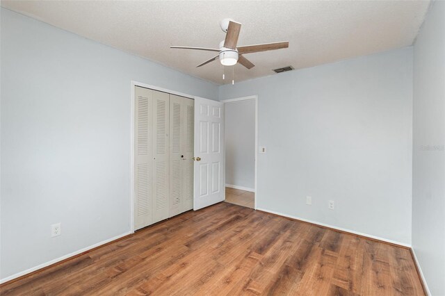 450 S Buena Vista Ave, Orlando, FL 32835 - unfurnished bedroom featuring wood finished floors, a closet, baseboards, ceiling fan, and a textured ceiling