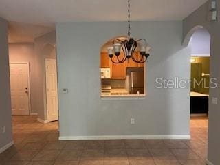 8775 Sartori St Unit 307, Orlando, FL 32829 - unfurnished dining area featuring arched walkways, a chandelier, baseboards, and tile patterned floors