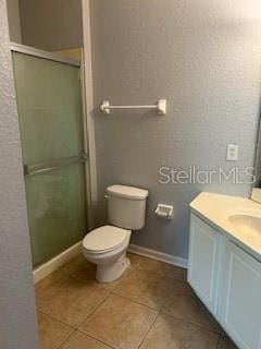 8775 Sartori St Unit 307, Orlando, FL 32829 - bathroom with vanity, a stall shower, tile patterned flooring, toilet, and baseboards