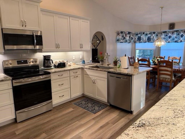 2 Bickshire Ln, Palm Coast, FL 32137 - kitchen with appliances with stainless steel finishes, a sink, a peninsula, decorative backsplash, and light wood finished floors