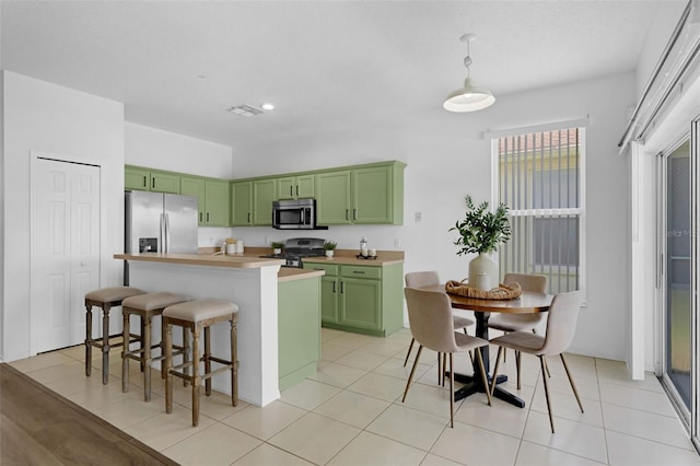 468 Jaybee Ave, Davenport, FL 33897 - kitchen with green cabinetry, appliances with stainless steel finishes, a kitchen island, a kitchen bar, and light countertops
