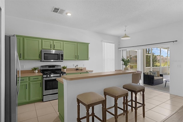 468 Jaybee Ave, Davenport, FL 33897 - kitchen with stainless steel appliances, green cabinets, a breakfast bar area, light countertops, and a textured ceiling