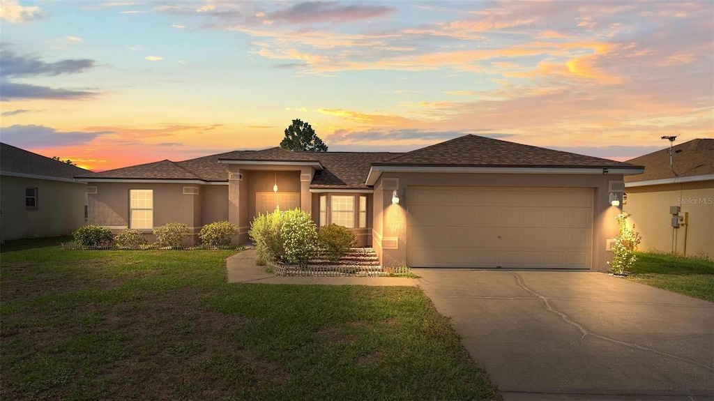 351 Cloverdale Rd, Winter Haven, FL 33884 - view of front of house featuring stucco siding, driveway, a garage, and a lawn