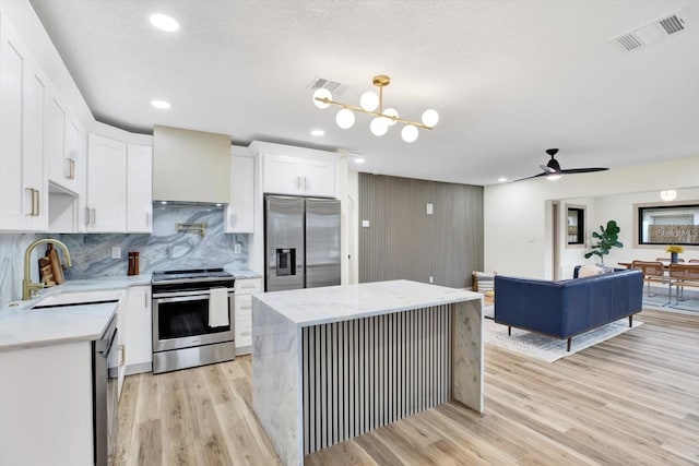 203 Driftwood Dr W, Palm Harbor, FL 34683 - kitchen with appliances with stainless steel finishes, a sink, wall chimney exhaust hood, light wood-style floors, and tasteful backsplash