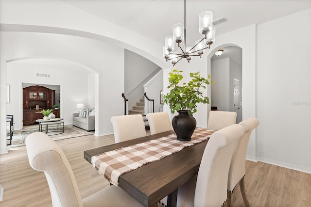 3868 Whitewood Ct, Oviedo, FL 32766 - dining space with arched walkways, stairway, a chandelier, light wood-style flooring, and baseboards