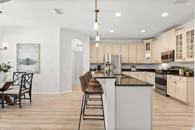 3868 Whitewood Ct, Oviedo, FL 32766 - kitchen with stainless steel appliances, a sink, cream cabinetry, arched walkways, and light wood-type flooring