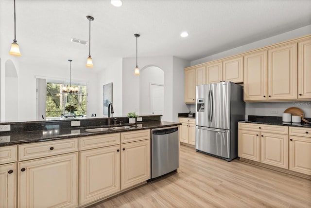 3868 Whitewood Ct, Oviedo, FL 32766 - kitchen featuring appliances with stainless steel finishes, a sink, cream cabinets, arched walkways, and decorative light fixtures