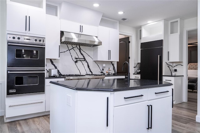 6917 Roman Ct, Clermont, FL 34714 - kitchen featuring under cabinet range hood, multiple ovens, high end fridge, a center island with sink, and light wood finished floors