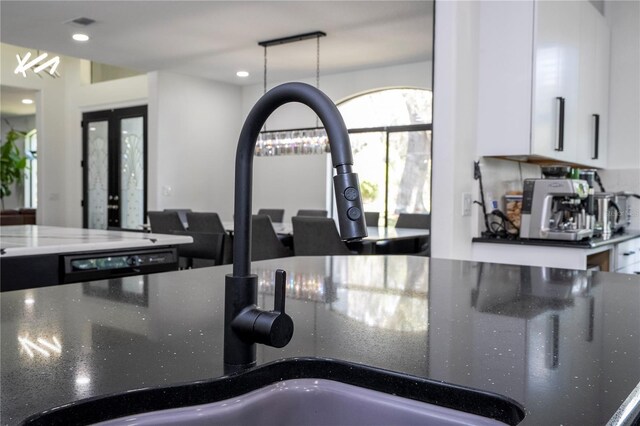 6917 Roman Ct, Clermont, FL 34714 - kitchen view of dark stone counters, white cabinetry, pendant lighting, french doors, and recessed lighting