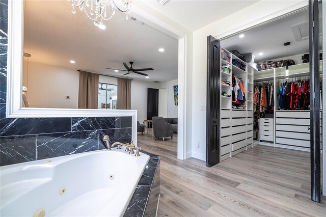 6917 Roman Ct, Clermont, FL 34714 - full bath with a ceiling fan, wood finished floors, a walk in closet, a tub with jets, and recessed lighting