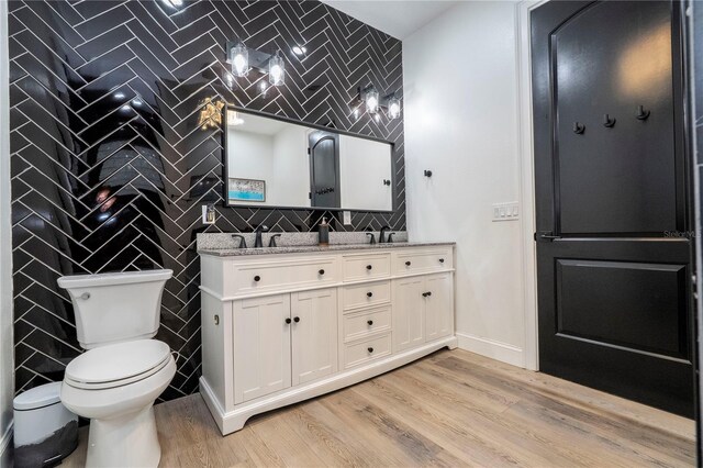 6917 Roman Ct, Clermont, FL 34714 - full bathroom featuring toilet, wood finished floors, baseboards, double vanity, and tile walls