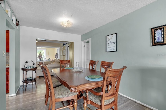 7500 NW 66th Ter, Tamarac, FL 33321 - dining room with light wood-style flooring, a textured ceiling, and baseboards