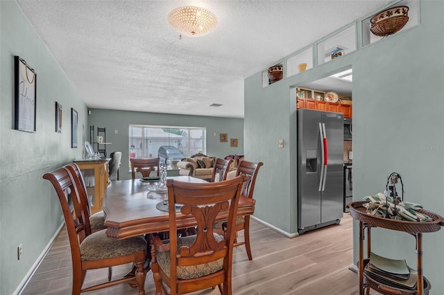 7500 NW 66th Ter, Tamarac, FL 33321 - dining room with a textured ceiling, light wood-style flooring, and baseboards
