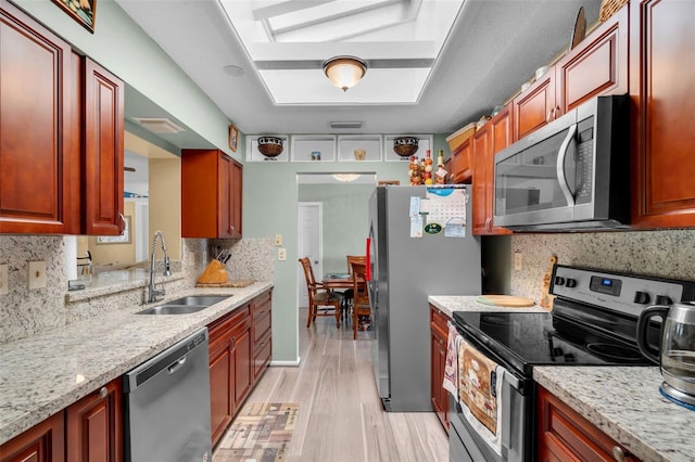 7500 NW 66th Ter, Tamarac, FL 33321 - kitchen featuring appliances with stainless steel finishes, a sink, light wood finished floors, decorative backsplash, and light stone counters