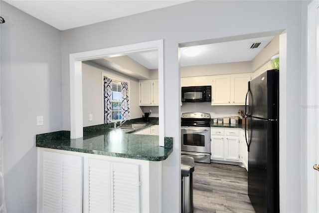117 Georgetown Dr Unit C, Casselberry, FL 32707 - kitchen with black appliances, a peninsula, wood finished floors, white cabinets, and a sink