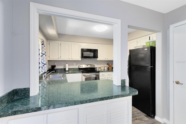 117 Georgetown Dr Unit C, Casselberry, FL 32707 - kitchen with black appliances, a sink, dark countertops, white cabinetry, and a peninsula