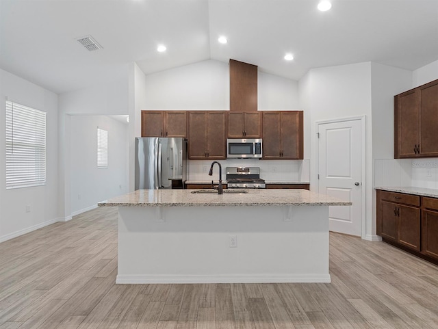 12009 Walmsley Aly, Winter Garden, FL 34787 - kitchen featuring appliances with stainless steel finishes, a sink, a kitchen island with sink, light stone countertops, and high vaulted ceiling