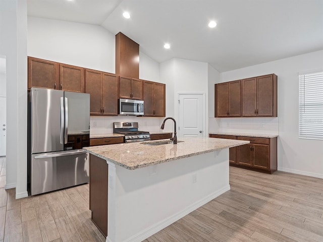 12009 Walmsley Aly, Winter Garden, FL 34787 - kitchen featuring appliances with stainless steel finishes, a sink, light wood-style floors, baseboards, and light stone counters