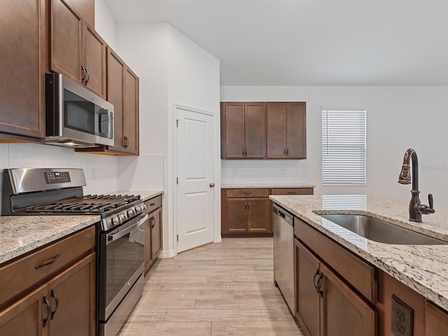 12009 Walmsley Aly, Winter Garden, FL 34787 - kitchen featuring appliances with stainless steel finishes, a sink, light wood-style floors, and light stone counters