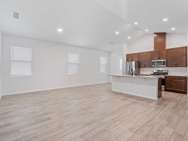 12009 Walmsley Aly, Winter Garden, FL 34787 - kitchen featuring stainless steel appliances, light wood finished floors, an island with sink, a breakfast bar, and high vaulted ceiling