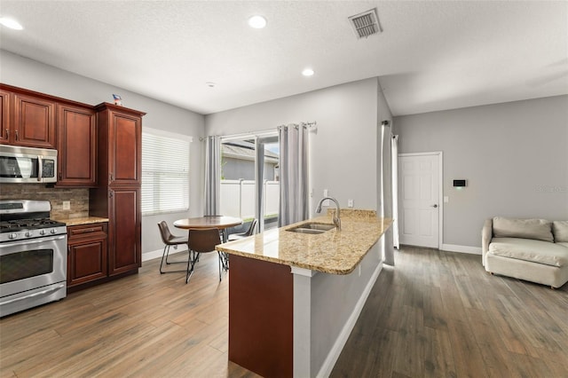 5032 Beach River Rd, Windermere, FL 34786 - kitchen with stainless steel appliances, a sink, baseboards, dark wood-style floors, and backsplash