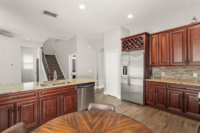5032 Beach River Rd, Windermere, FL 34786 - kitchen with stainless steel appliances, a sink, dark wood-style floors, reddish brown cabinets, and tasteful backsplash