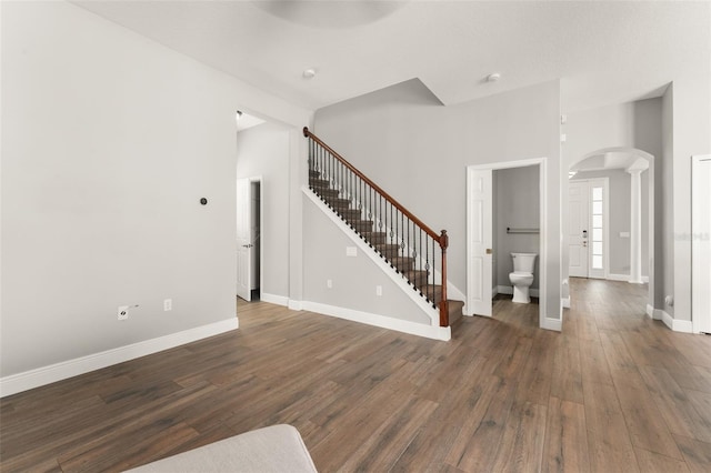 5032 Beach River Rd, Windermere, FL 34786 - unfurnished living room with arched walkways, stairway, wood finished floors, and baseboards