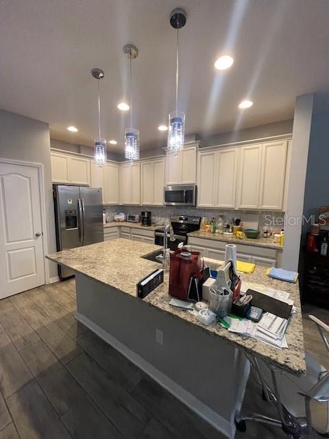 2937 Econ Landing Blvd, Orlando, FL 32825 - kitchen featuring stainless steel appliances, pendant lighting, wood finished floors, a sink, and decorative backsplash