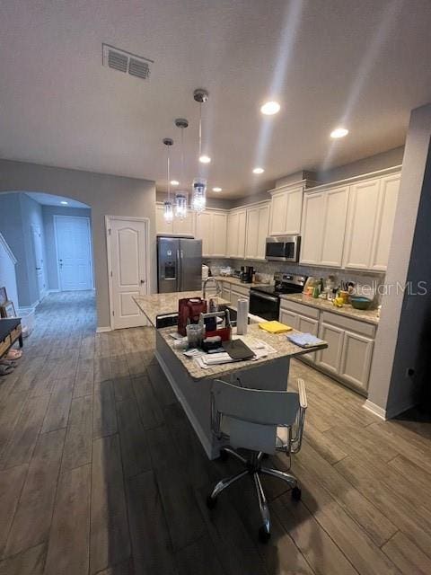 2937 Econ Landing Blvd, Orlando, FL 32825 - kitchen with appliances with stainless steel finishes, dark wood-type flooring, arched walkways, a center island with sink, and white cabinets