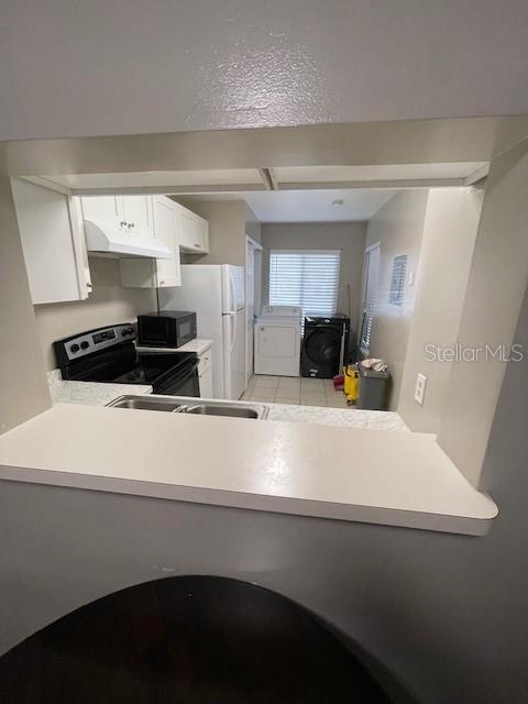 2236 Stonington Ave Unit 2236, Orlando, FL 32817 - kitchen featuring electric stove, under cabinet range hood, independent washer and dryer, black microwave, and light countertops