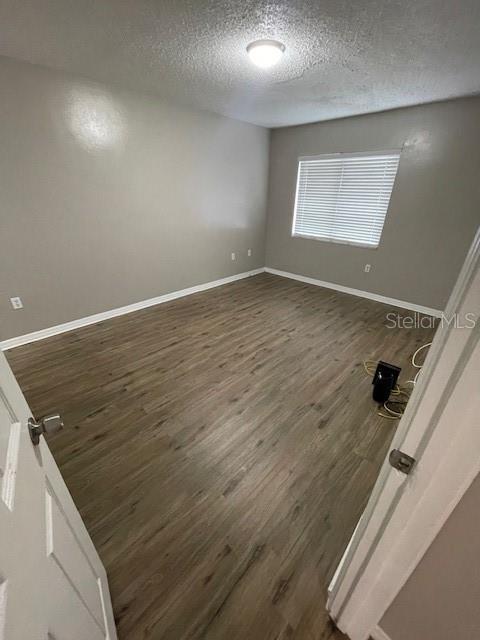 2236 Stonington Ave Unit 2236, Orlando, FL 32817 - empty room with a textured ceiling, dark wood-style flooring, and baseboards