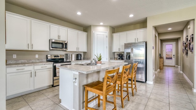 600 Buchannan Dr, Davenport, FL 33837 - kitchen with stainless steel appliances, light tile patterned flooring, light countertops, a sink, and a kitchen island with sink