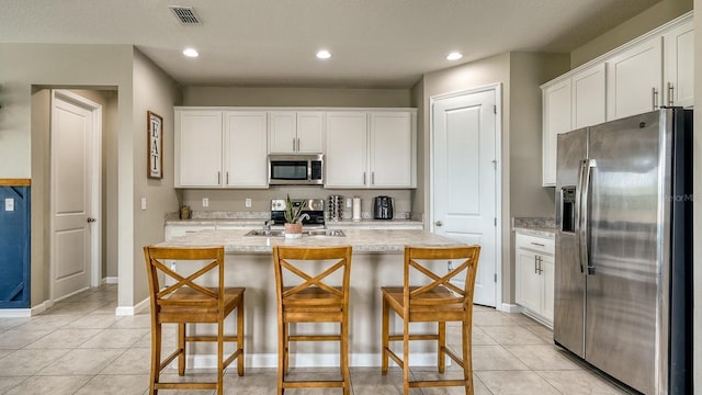 600 Buchannan Dr, Davenport, FL 33837 - kitchen with stainless steel appliances, light countertops, white cabinetry, a breakfast bar, and recessed lighting