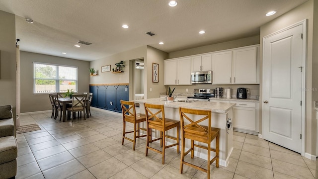 600 Buchannan Dr, Davenport, FL 33837 - kitchen featuring appliances with stainless steel finishes, white cabinets, recessed lighting, light tile patterned floors, and a kitchen bar