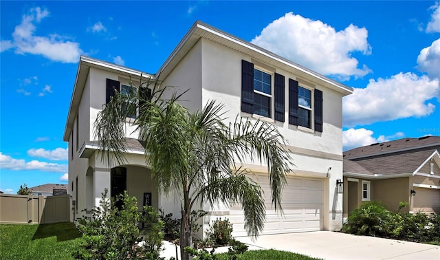 view of front of house with stucco siding, an attached garage, driveway, and a gate
