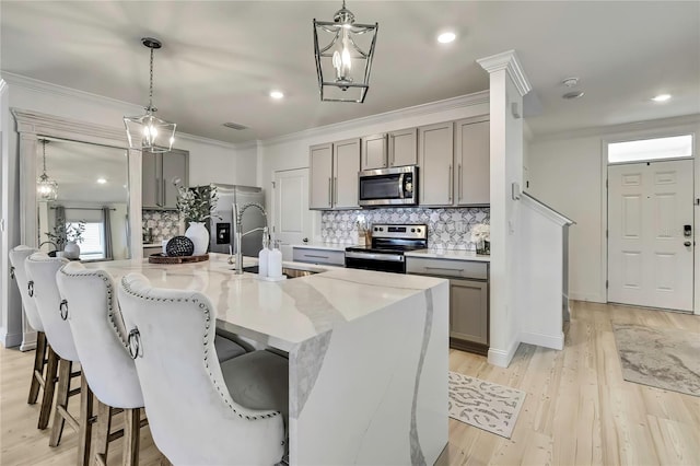 kitchen featuring appliances with stainless steel finishes, gray cabinetry, a sink, tasteful backsplash, and crown molding