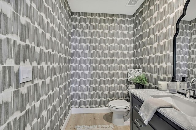 bathroom with toilet, vanity, tile walls, and wood finished floors