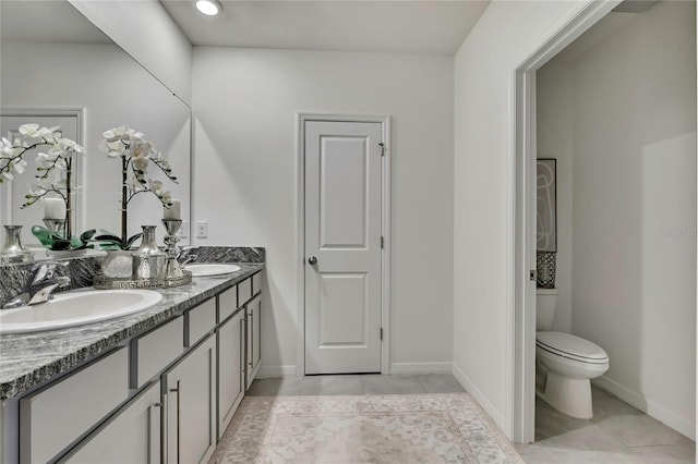 bathroom with double vanity, toilet, baseboards, and tile patterned floors