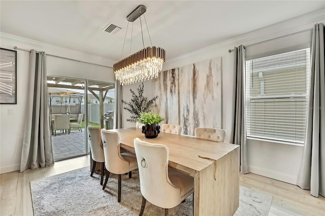 dining space with a chandelier, light wood finished floors, baseboards, and crown molding