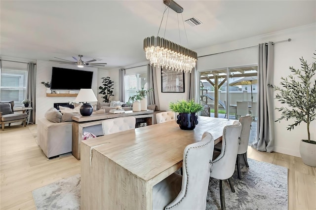 dining room featuring light wood-style flooring, a ceiling fan, a chandelier, and a fireplace