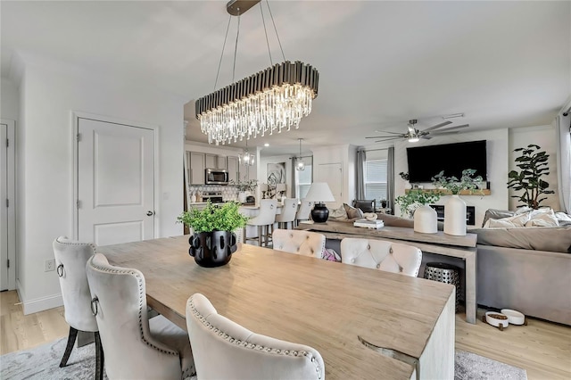dining room featuring light wood finished floors, a ceiling fan, and a chandelier