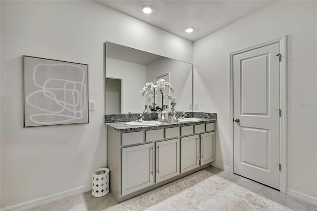 bathroom with baseboards, double vanity, and tile patterned flooring