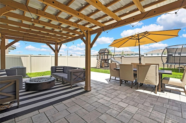 fenced backyard with a trampoline, a playground, a patio area, outdoor dining area, and an outdoor living space with a fire pit