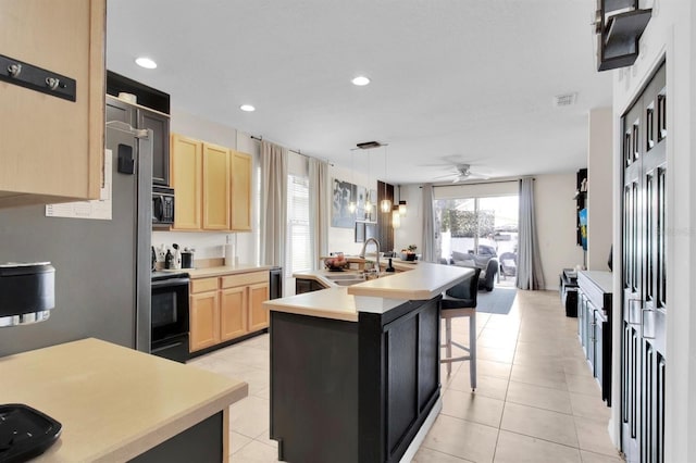 10293 Cypress Knee Cir, Orlando, FL 32825 - kitchen featuring light brown cabinets, range with electric stovetop, a sink, a kitchen island with sink, and light countertops