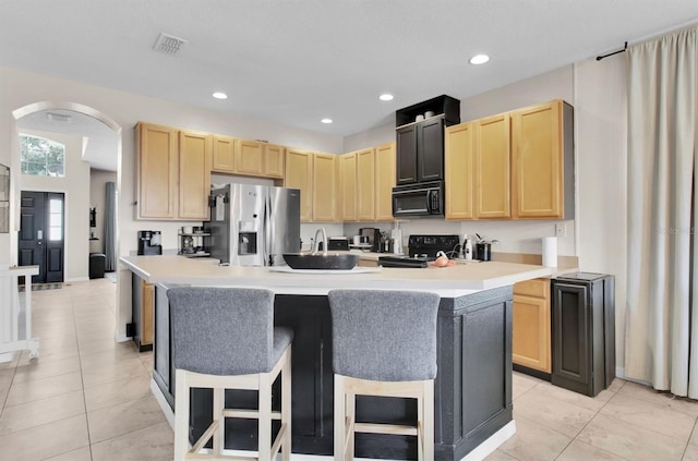 10293 Cypress Knee Cir, Orlando, FL 32825 - kitchen with black appliances, light brown cabinets, arched walkways, an island with sink, and recessed lighting