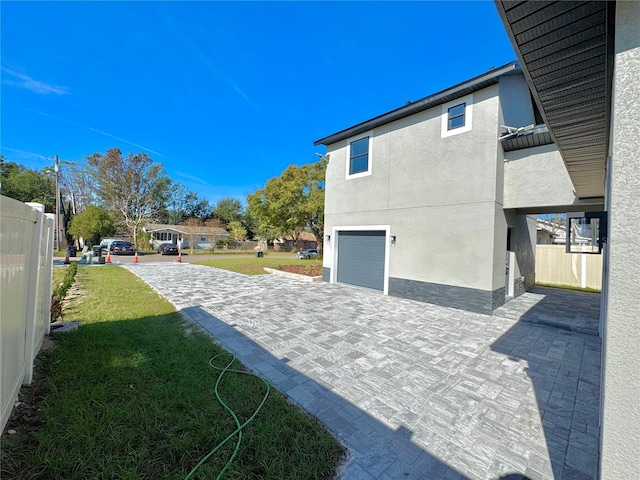 107 Grove St, Orlando, FL 32835 - view of side of property with a garage, stucco siding, a yard, and decorative driveway