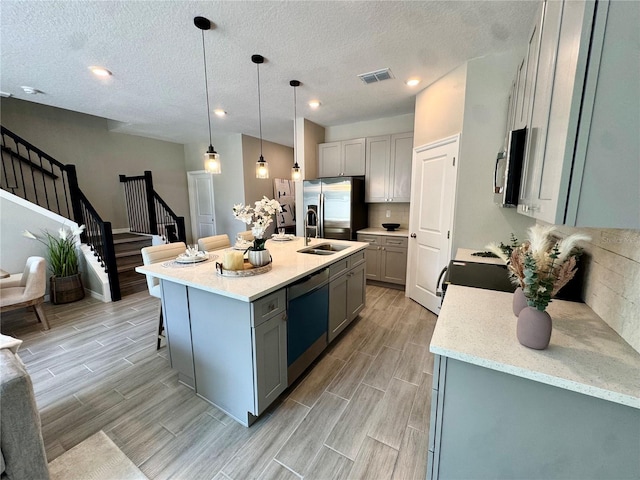 107 Grove St, Orlando, FL 32835 - kitchen with gray cabinets, stainless steel appliances, a sink, wood finish floors, and a textured ceiling
